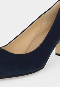 Escarpin en daim bleu marine à talon moyen, doublure intérieure beige et bout carré arrondi sur fond blanc.