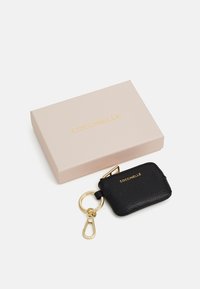 Portachiavi in pelle nera con hardware dorato, dotato di chiusura con zip e logo impresso. È posizionato accanto a una scatola di colore rosa chiaro.