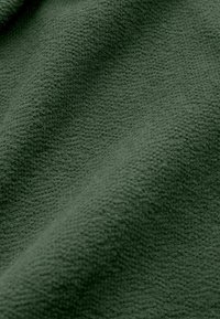 Țesătură verde texturată, cu o suprafață moale, țesută, având un model subtil și un aspect drapat.