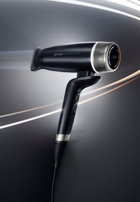 Sèche-cheveux ghd Speed noir avec affichage numérique et flux d'air, sur fond sombre avec effets de traînées lumineuses.
