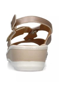 Infradito beige con suola bianca, cinturini regolabili e soletta imbottita. Presenta un design elegante e dettagli hardware metallici.