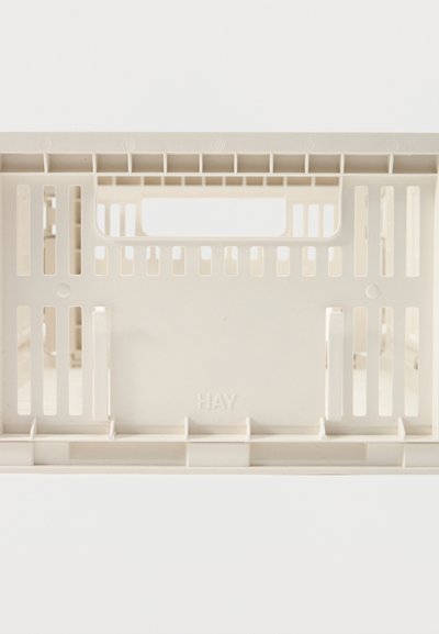 Caisses de rangement empilées en plastique beige avec des fentes de ventilation rectangulaires et des poignées intégrées sur fond blanc.