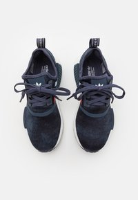 Tyrkysově modré sportovní boty s texturovaným látkovým svrškem, kontrastními černými detaily, bílými podešvemi a plochými tkaničkami. Mají zadní poutko na snadné nazouvání.
