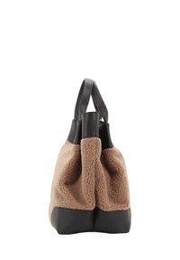 Tote en shearling marron avec des accents en cuir noir, doté de deux poignées et d'une base structurée pour la stabilité. La texture douce contraste avec le cuir lisse.