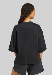 Sort oversized t-shirt med korte ærmer, rund hals og en glat stofstruktur. Har en afslappet pasform og sideslids for let bevægelse.