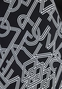 Mönstrad tyg med vita geometriska former och linjer på en svart bakgrund med en mjuk textur.