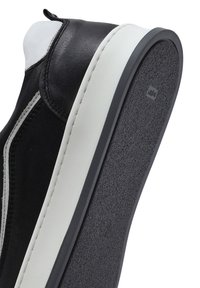 Czarne skórzane sneakersy z białym akcentem, teksturowana szara gumowa podeszwa, zaokrąglony kształt i minimalne przeszycia wzdłuż boków.