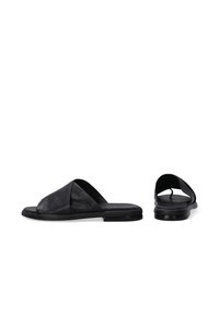 Sandales à glissière en cuir noir avec un design de bandes en croix, semelle plate et texture lisse. Style minimaliste adapté pour une tenue décontractée.
