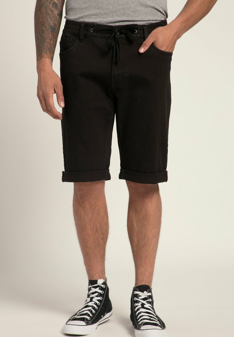 Pantaloni short in denim nero con vestibilità dritta, orli arrotolati e vita con cordoncino elastico. Indossati con sneakers nere alte.
