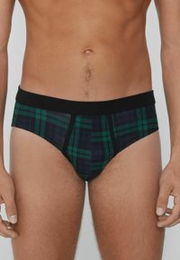 Herren-Bikini mit einem schwarzen elastischen Bund und einem Karomuster in Grüntönen und Marineblau. Das Material wirkt glatt und hat eine figurbetonte Passform.