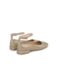 Ballerine in pelle verniciata beige con cinturino alla caviglia, caratterizzate da un motivo a griglia di piccoli chiodini metallici sulla tomaia e un tacco basso a blocco.