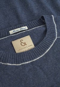 Marinefarbener Merinowollpullover mit geripptem Kragen, ausgestattet mit einem kontrastierenden weißen Stichdetail und einem hellbraunen Lederetikett mit geprägt Text.