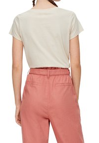 Camiseta beige lisa con escote redondo combinada con pantalones de tiro alto, de corte relajado y color rosa claro, con cinturilla elástica y bolsillos laterales.