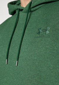Felpa verde realizzata in tessuto testurizzato con cappuccio regolabile. Caratterizzata da un logo ricamato discreto sul petto e un cordino coordinato.