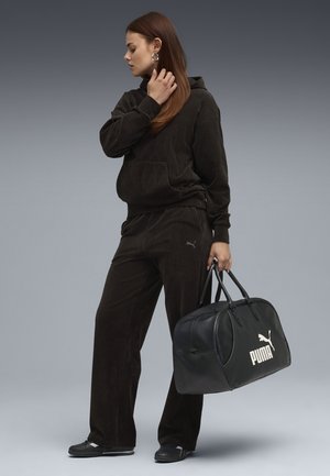 Dark brown corduroy hoodie and pants with front pocket, paired with a black leather duffel bag featuring a white Puma logo.