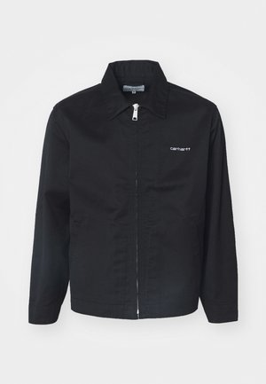 Black jacket made of durable fabric, featuring a zip closure, pointed collar, and side pockets. Includes white logo detail on the chest.