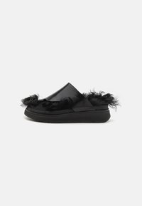 Svarta slip-on skor med ett glansigt material och texturerade svarta pälsdetaljer längs ovandelen. Har en platt gummisula.