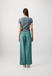 Lyseblå kortermet skjorte, kombinert med vide teal bukser. Slim fit topp, teksturert stoff og skreddersydd design med baklommer.