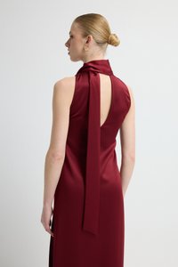 Bordowa sukienka bez rękawów z wysokim kołnierzem i odsłoniętymi plecami. Posiada długi materiałowy pasek i gładką, satynową fakturę.