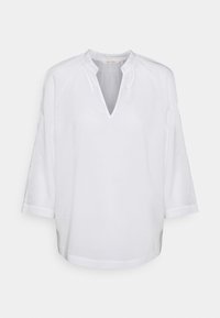 Blouse blanche à manches longues avec un col en V et un col froncé, présentant une coupe ample et un design simple.
