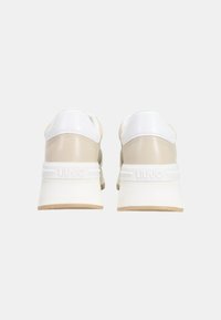 Sneaker beige e bianche con tomaia in pelle liscia, colletto imbottito e suola texturizzata. Presentano un logo discreto sul tallone e un design pulito.