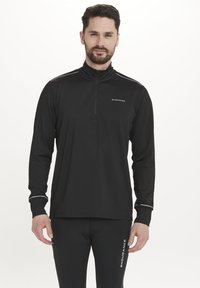 Sort langærmet zip-up sports top med hvide accenter og logo. Glat stof, tætsiddende design, høj krave, inklusive reflekterende detaljer.