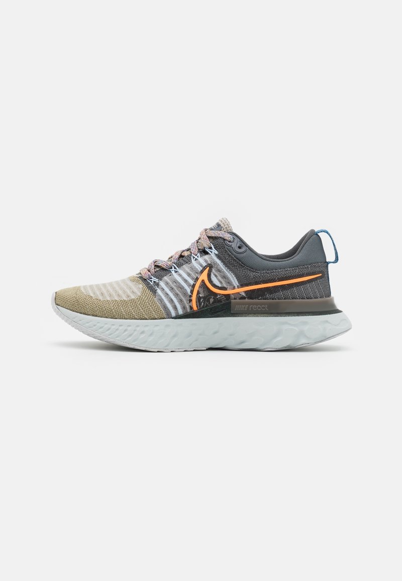 Chaussure de course Nike React légère avec tige en maille beige et grise, swoosh orange, et semelle blanche amortissante.