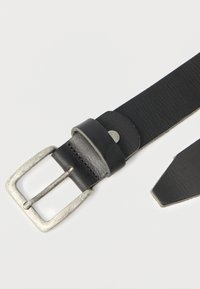 Cinto de couro preto com acabamento texturizado, apresentando uma fivela de metal prateado e um passante. A extremidade é pontiaguda e o cinto tem forma plana.