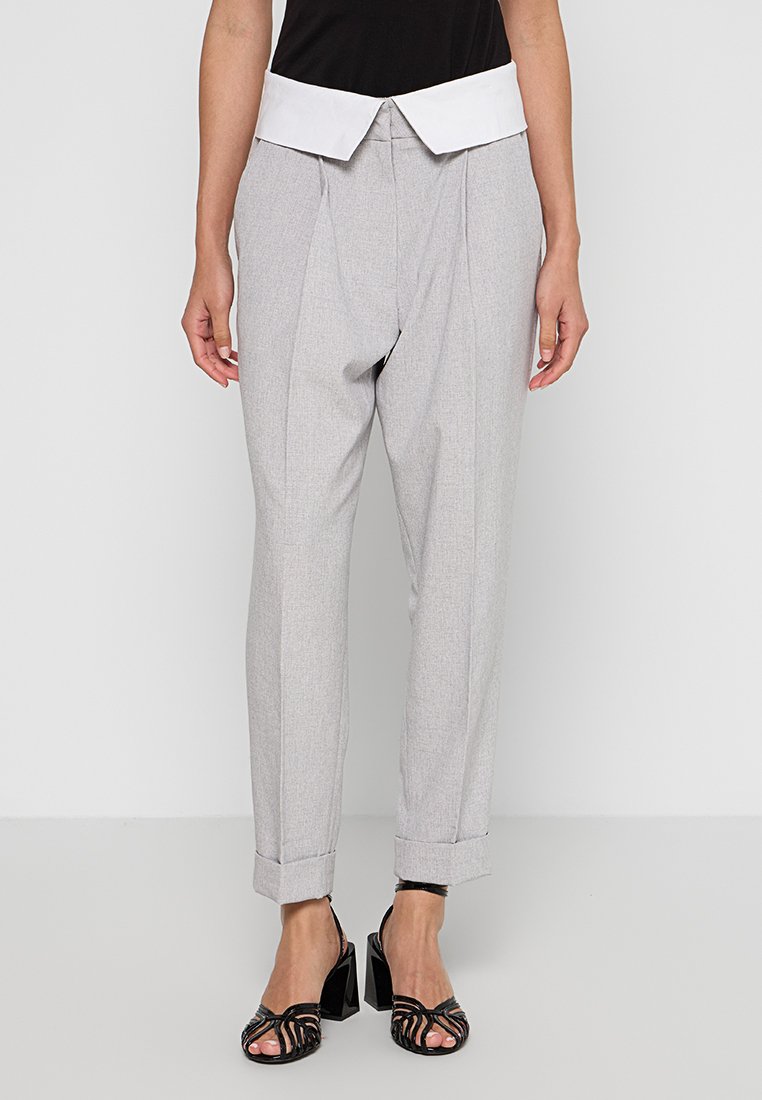 Gray tailored trousers with a white folded waistband, featuring a relaxed fit, pleats, and turn-up cuffs. Paired with black strappy heels.