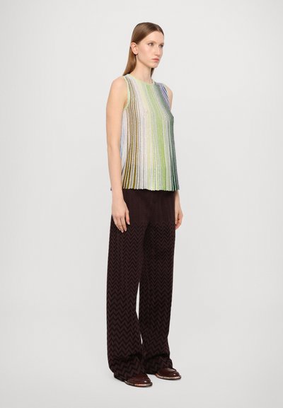 Top sin mangas con rayas verticales de colores en verde, azul y blanco; combinado con pantalones anchos de patrón zigzag marrón.