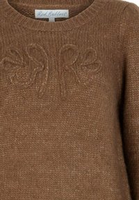 Bruine gebreide trui met verhoogde bloemenpatronen op de borst en een "Red Button" label bij de hals.