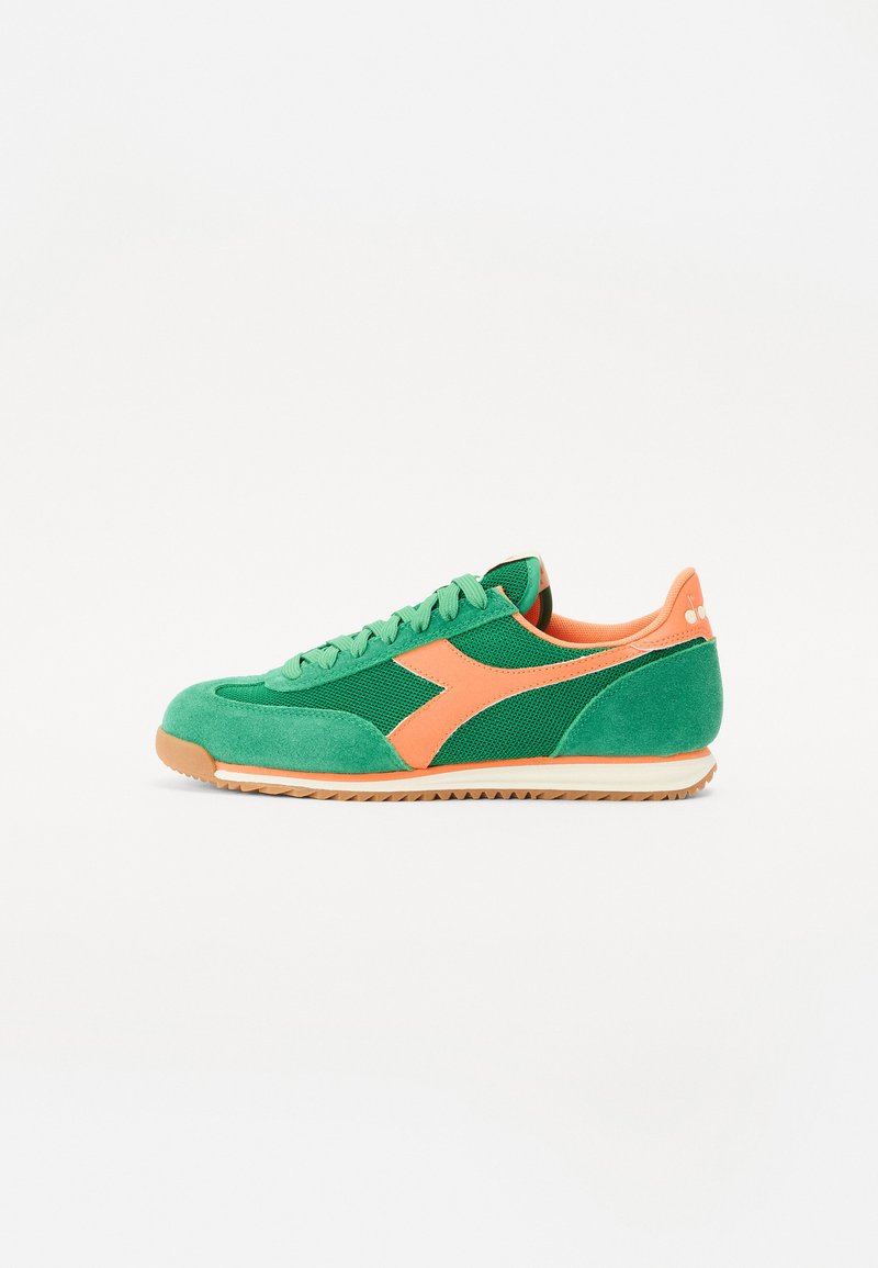 Grønn semsket og mesh sneaker med oransje detaljer, som har rund tå, flate lisser og en lysebrun gummisåle.