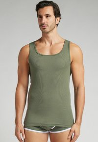Olivgrön ribbad linne med rund halsringning, tillsammans med matchande shorts med vit kant. Mjuk, figurnära tygtextur.
