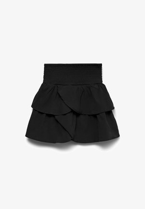 Zwarte tiered mini rok met een hoog smocktail en een gelaagd ruffle ontwerp op een witte achtergrond.