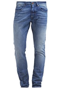 Jeans de mezclilla azul con un lavado desgastado, corte ajustado, cinco bolsillos y sutiles detalles desgastados en la parte frontal. Cierre clásico de botón y cremallera.