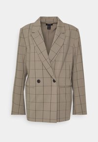 Blazer beige à double boutonnage avec des lignes en grille foncées, deux boutons devant, revers crantés et manches longues.