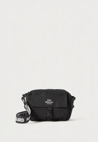 Borsa a tracolla rettangolare nera con patta frontale, fibbia in plastica e tracolla regolabile stampata con il testo "NØRGAARD".