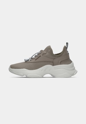 Sneaker lavorato a maglia marrone chiaro con suola bianca spessa, lacci elasticizzati e linguetta sul tallone, mostrato dal lato sinistro su uno sfondo semplice.