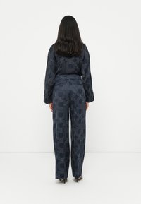 Navy patterned blouse with long sleeves and matching wide-leg trousers, featuring geometric outlines. Smooth fabric texture.