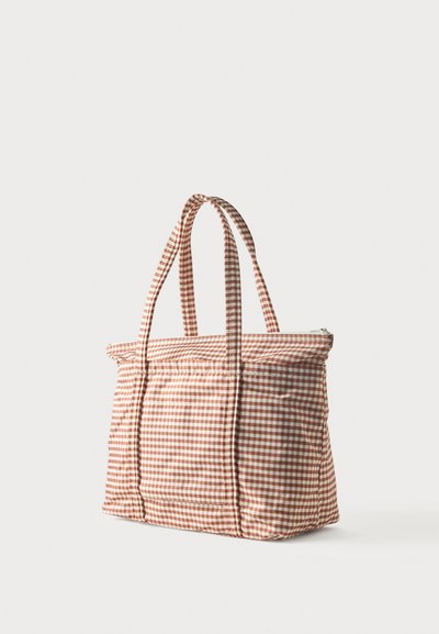 Καρό τσάντα ώμου από καφέ και άσπρο ύφασμα gingham με δύο λαβές και φερμουάρ στο πάνω μέρος, όρθια σε λευκό φόντο.