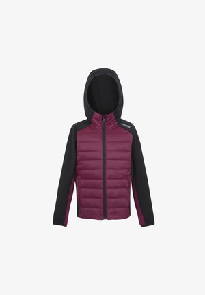 Niño con gorro negro, chaqueta maroon y negra con cremallera, pantalones negros y zapatillas negras, de pie frente a un fondo claro y liso.