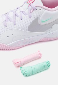 Scarpa sportiva bianca con accenti lilla e suola maculata rosa. Include lacci rosa e menta. Parte superiore in rete per traspirabilità.