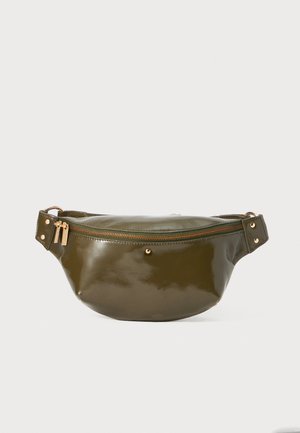 Oliwkowa nerka wykonana z błyszczącego materiału, z złotym zamkiem błyskawicznym, bocznymi akcentami oraz zaokrąglonym, krzywym kształtem.