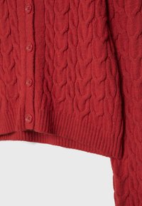 Cardigan rouge en maille torsadée avec fermeture boutonnée verticale et ourlet côtelé, montrant une texture de tricot détaillée et quatre boutons visibles.