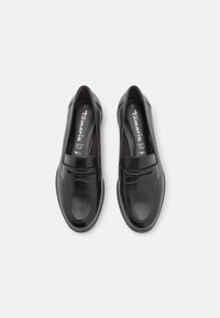 Zapatos negros de piel tipo mocasín con punta redonda, costuras decorativas y un tacón bajo; presentan un acabado suave y brillante con acentos sutiles.