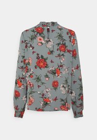 Blusa floral con fondo verde, que presenta flores rojas, rosas y blancas. Mangas largas con puños fruncidos y un detalle de cuello fruncido.