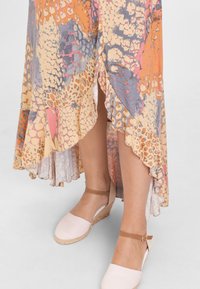Pestrý asymetrický šaty v pastelových odtieňoch s animal printom, s volánovým lemom a skombinované s ružovými espadrilkami.