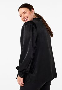 Čierna saténová blúzka s ruffles golierom, vyp puff sleeves a gombíkmi na manžetách. Hladká štruktúra s voľným strihom.