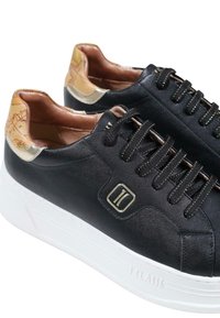 Sneakers sintetici neri con una finitura liscia, dettagli dorati e un tallone in pelle con motivo. Presentano lacci scuri e una suola in gomma bianca.