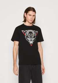 Zwarte katoenen t-shirt met een voorzijde graphic van het hoofd van een panter met gele ogen, geplaatst binnen een rode driehoekige omtrek.